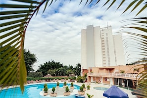 Una piscina al aire libre, sombrillas, sillones reclinables de piscina