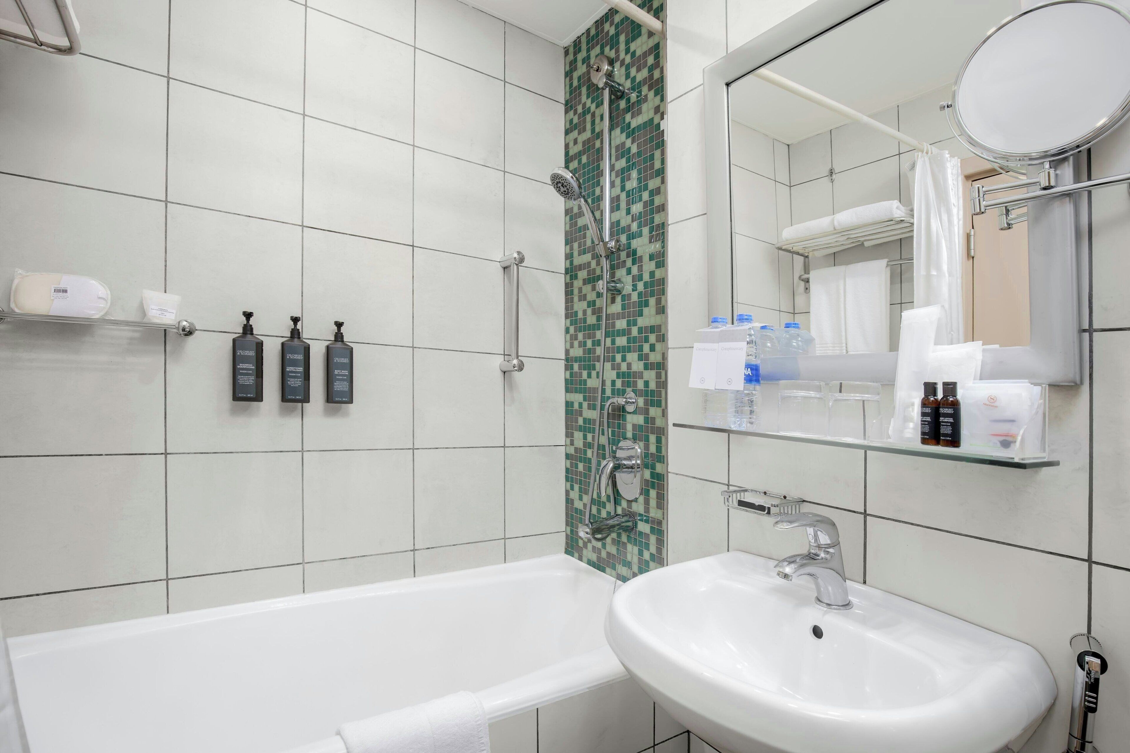 A modern bathroom with a bathtub, a sink, a shower, and a mirror.