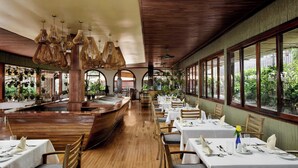 A restaurant with wooden tables and chairs, large windows, and hanging light fixtures. - Sheraton Kampala Hotel (Kampala)