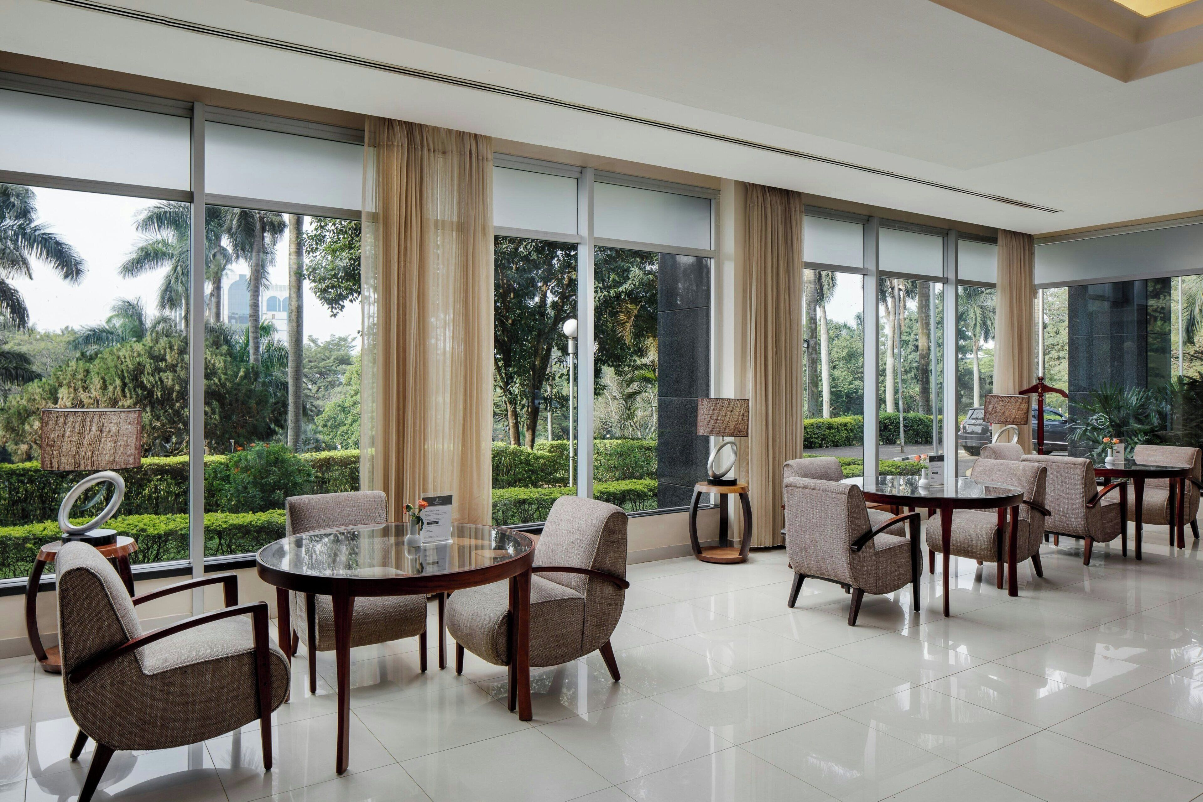 A spacious room with large windows, a round glass table, and several upholstered chairs.