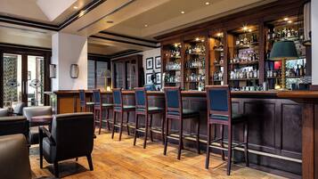 A bar with wooden bar stools and a variety of liquor bottles.