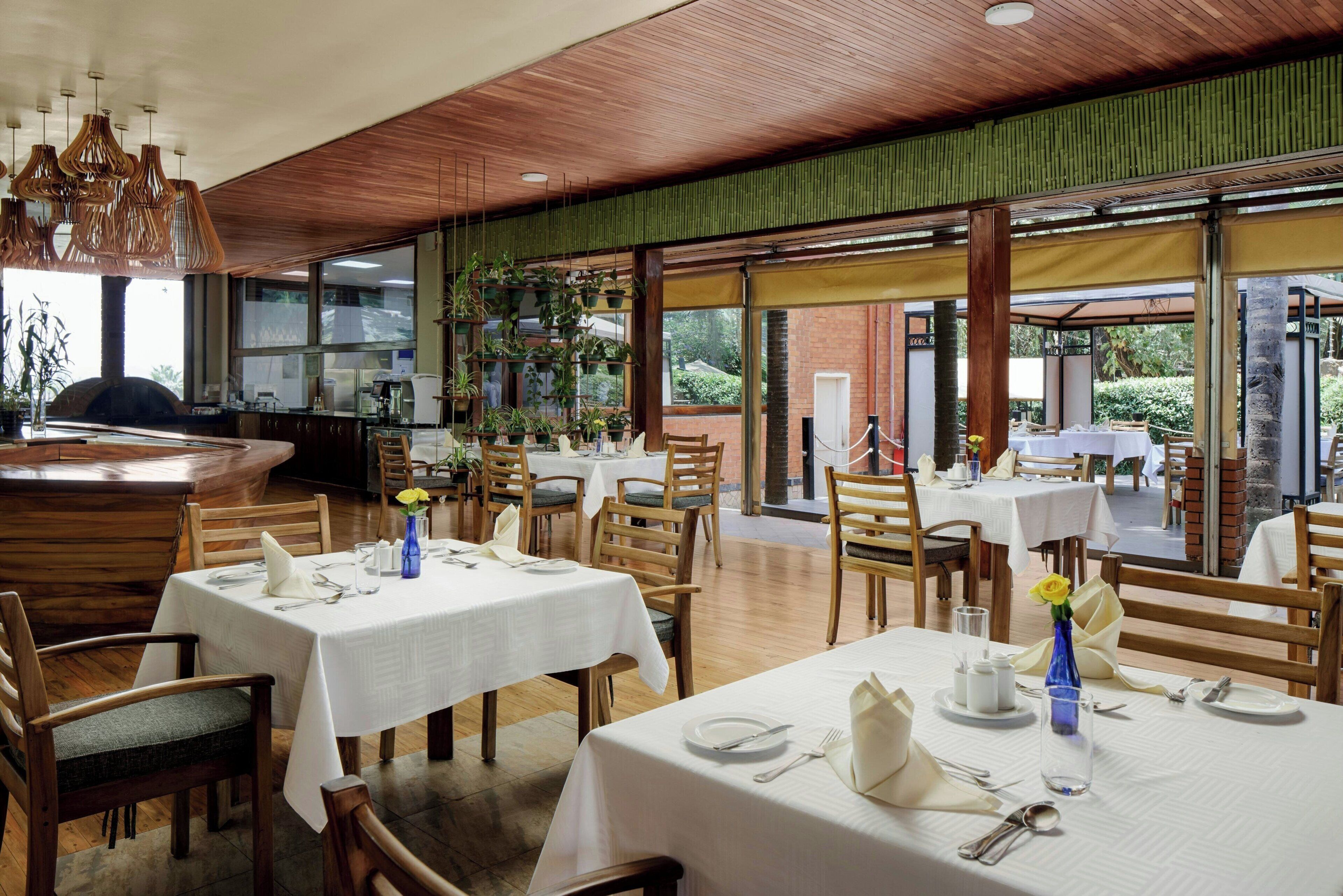 A restaurant with multiple tables, chairs, and hanging plants.