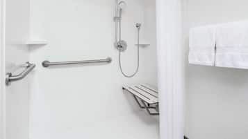 Un espacio de ducha moderno con cabezal de ducha manual, accesorio de ducha manual y barra de apoyo.