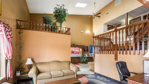A hotel lobby with a sofa, a desk, a staircase, and a reception area. - Econo Lodge Inn & Suites Fairview Heights - St. Louis (Fairview Heights)