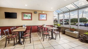 A restaurant with booths and tables, large windows, and a flat-screen TV on the wall. - Econo Lodge Inn & Suites Fairview Heights - St. Louis (Fairview Heights)