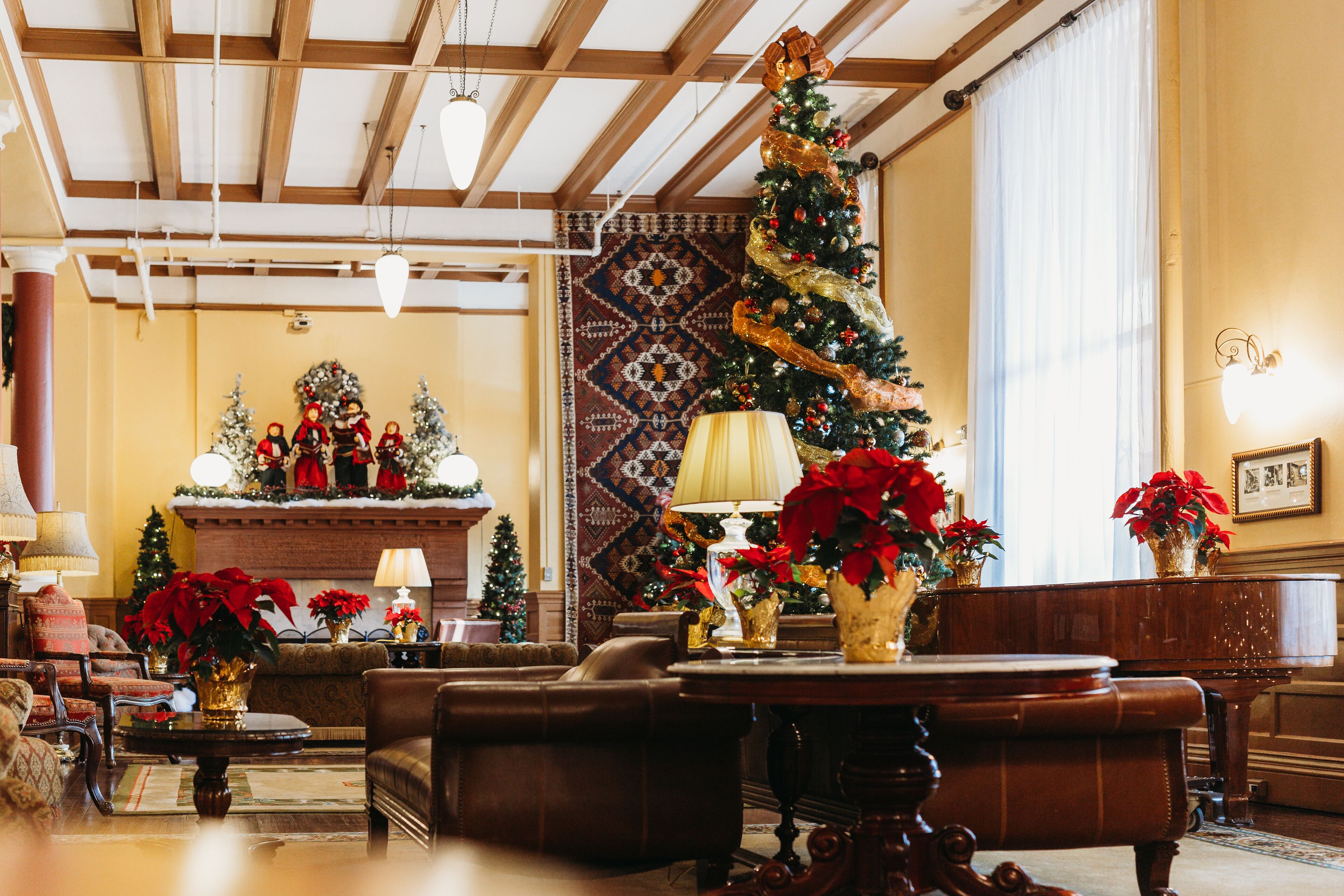 A cozy lobby with a large Christmas tree, a fireplace, and comfortable seating areas.
