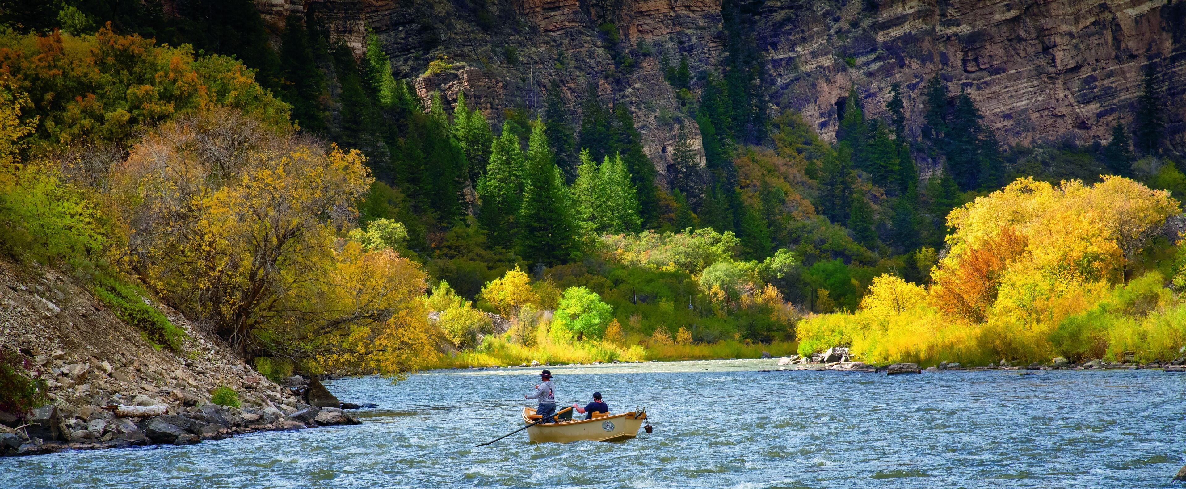 A river with a rocky bank and trees with autumn foliage.