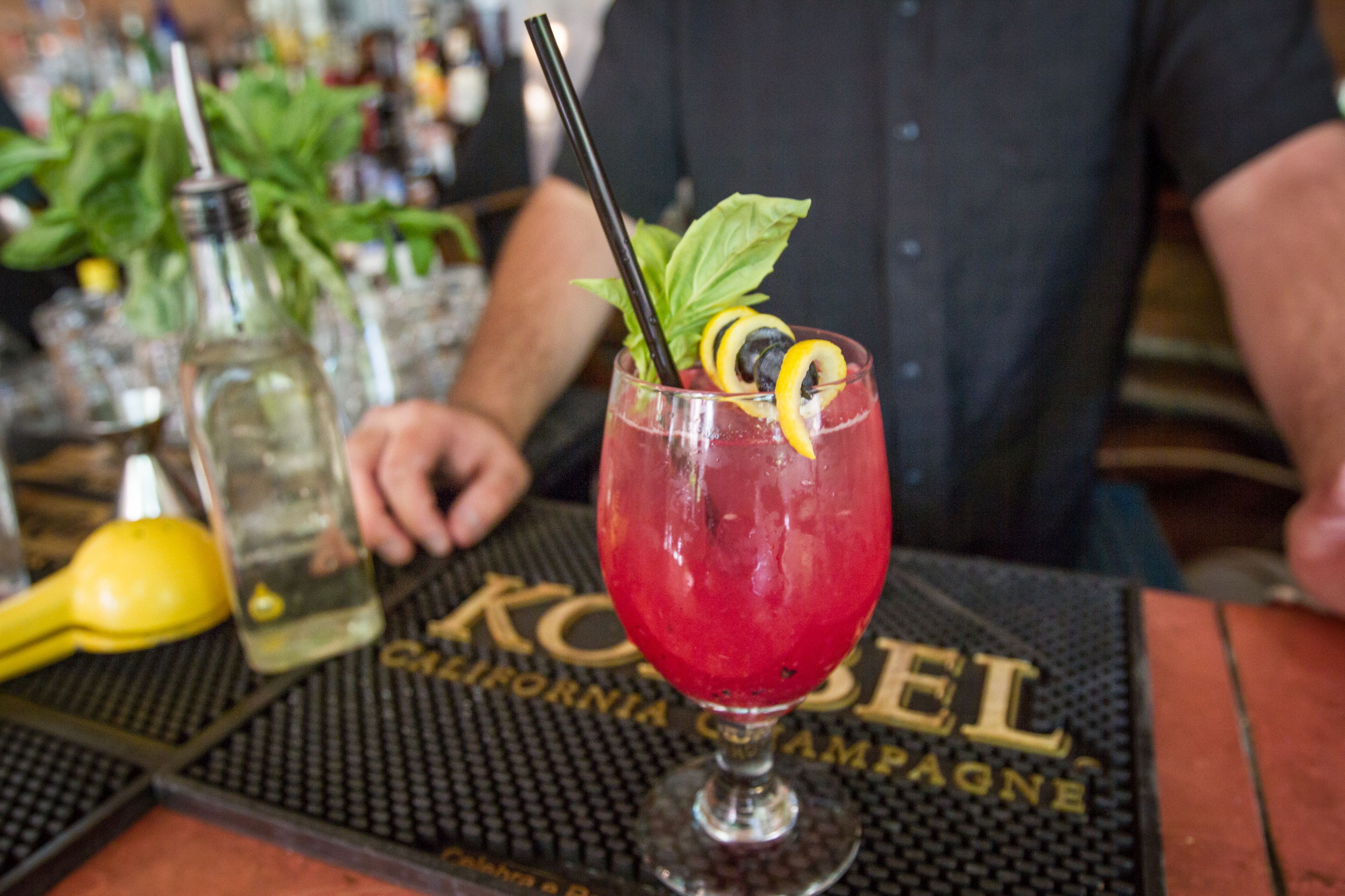 Een cocktail met rietje en garnering op een barmat met de tekst 'California Champagne'.