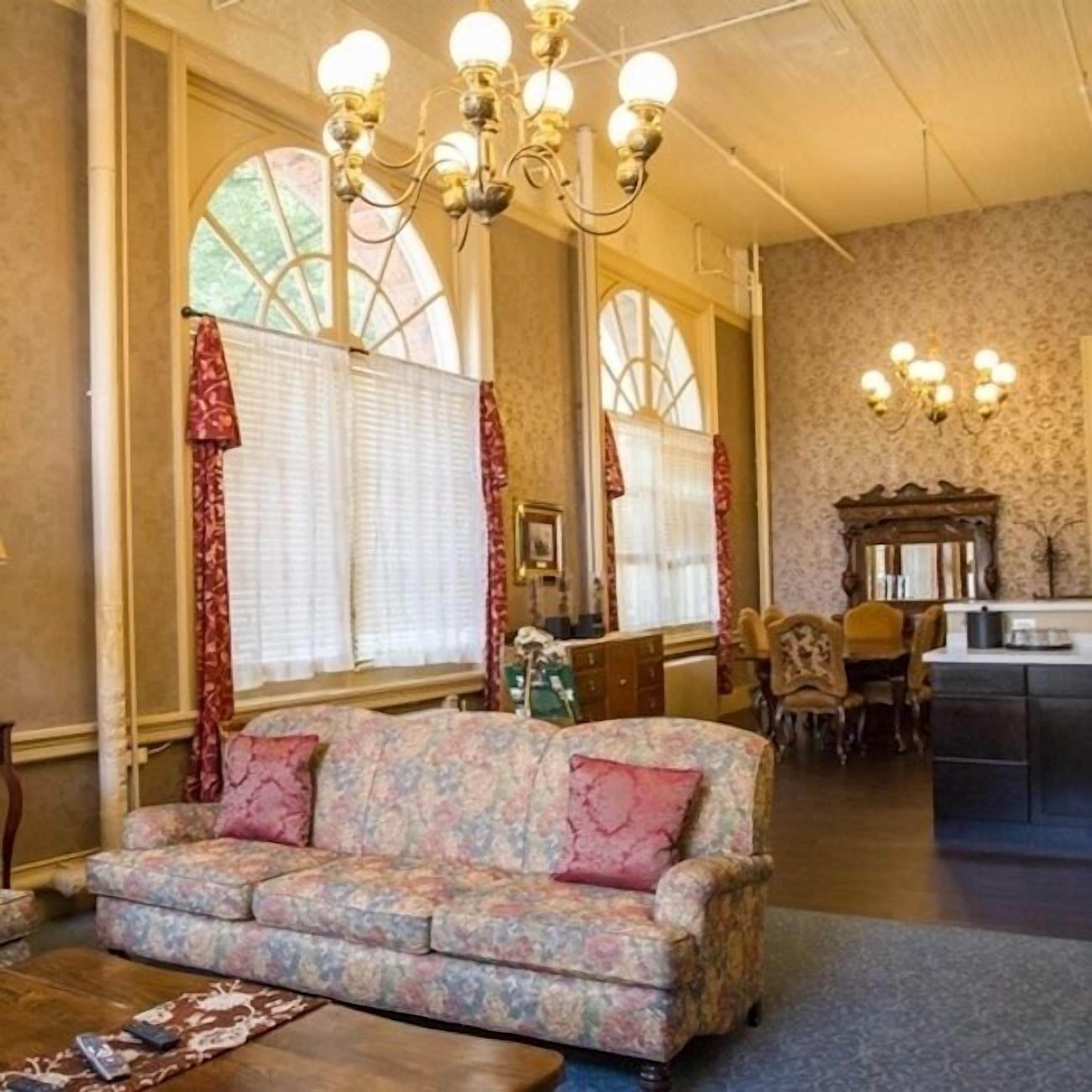 A room with a floral sofa, a dining area, and a kitchen.