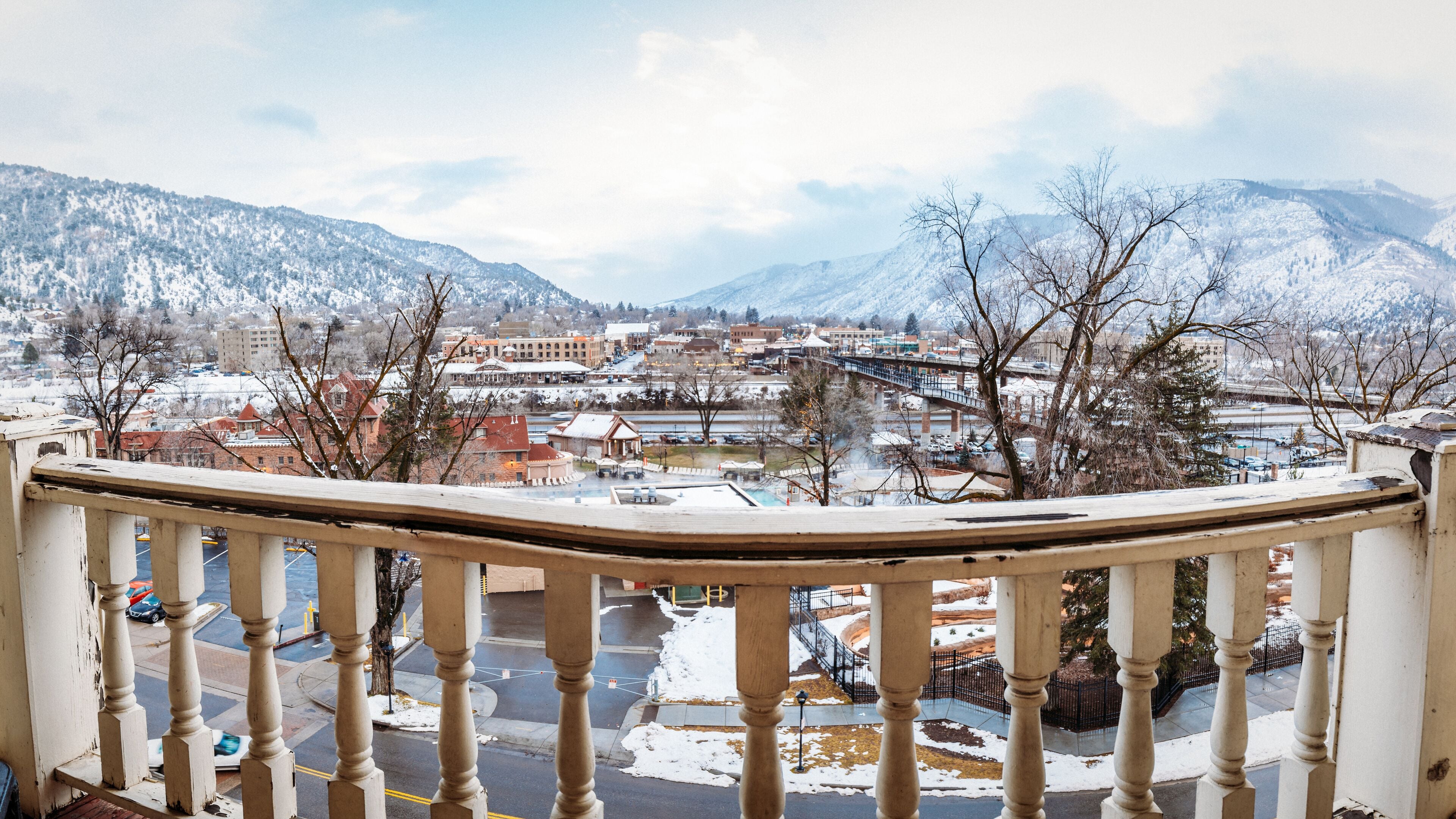 A balcony with a view of a snow-covered town and mountains.