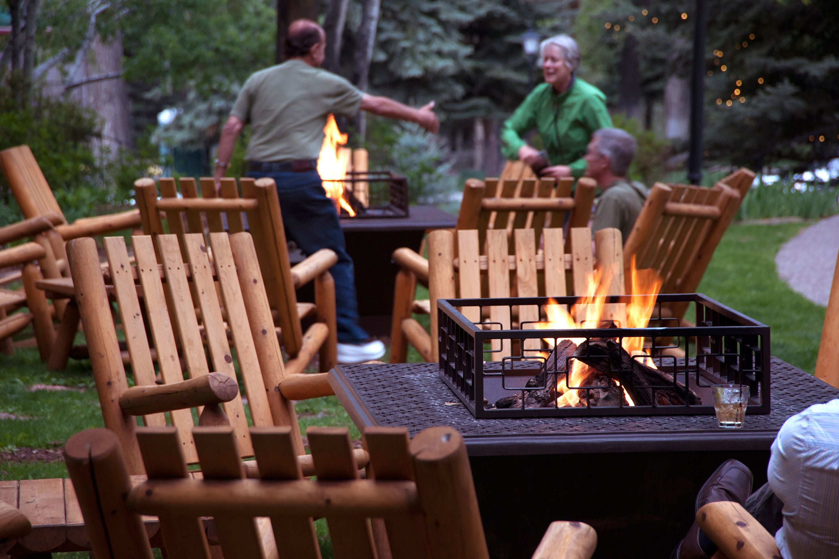 Outdoor seating with a fire feature, surrounded by trees.