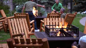 Outdoor seating with a fire feature, surrounded by trees.