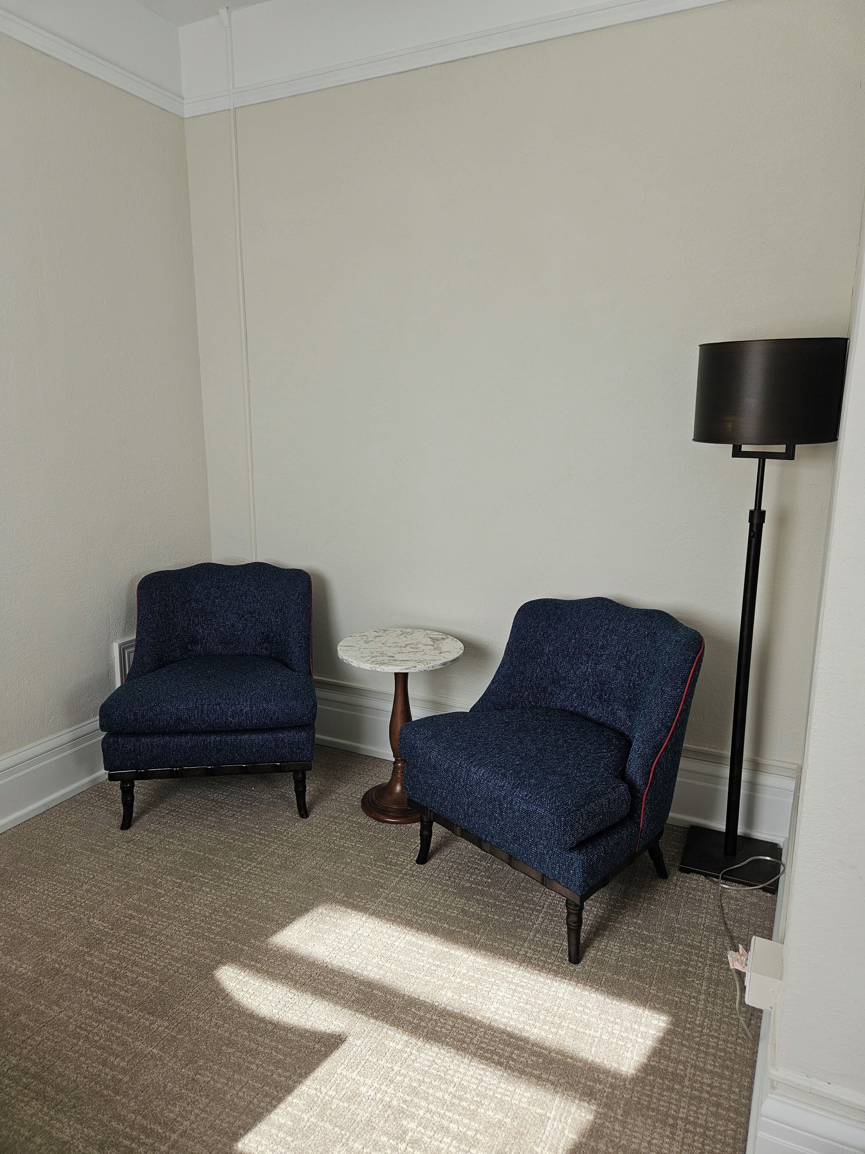 A room with two blue armchairs, a small round table, and a floor lamp.