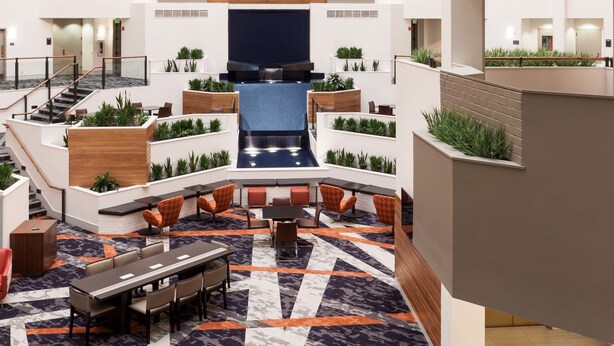 A multi-level atrium with a central seating area, a staircase, and a large screen.
