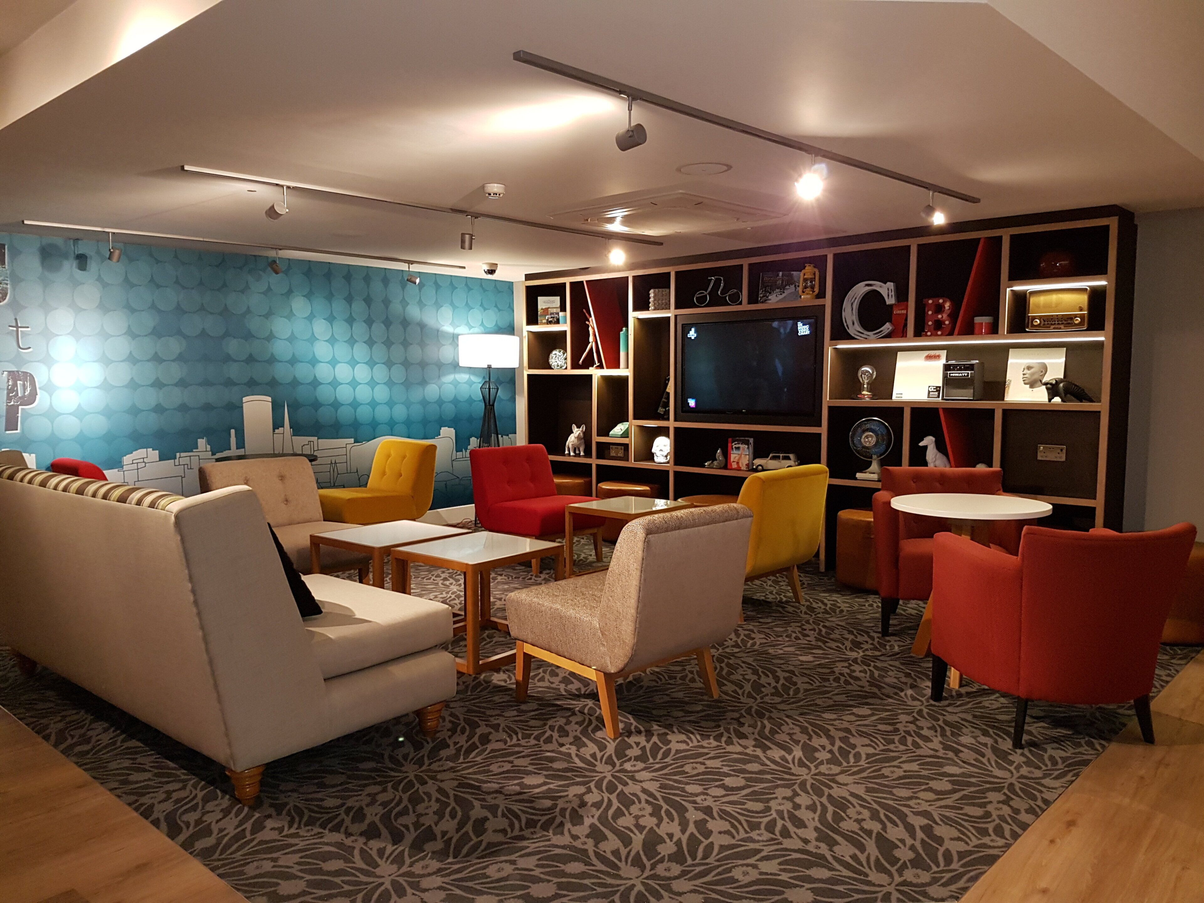 A modern living room with sofas, chairs, a TV, and a bookshelf.