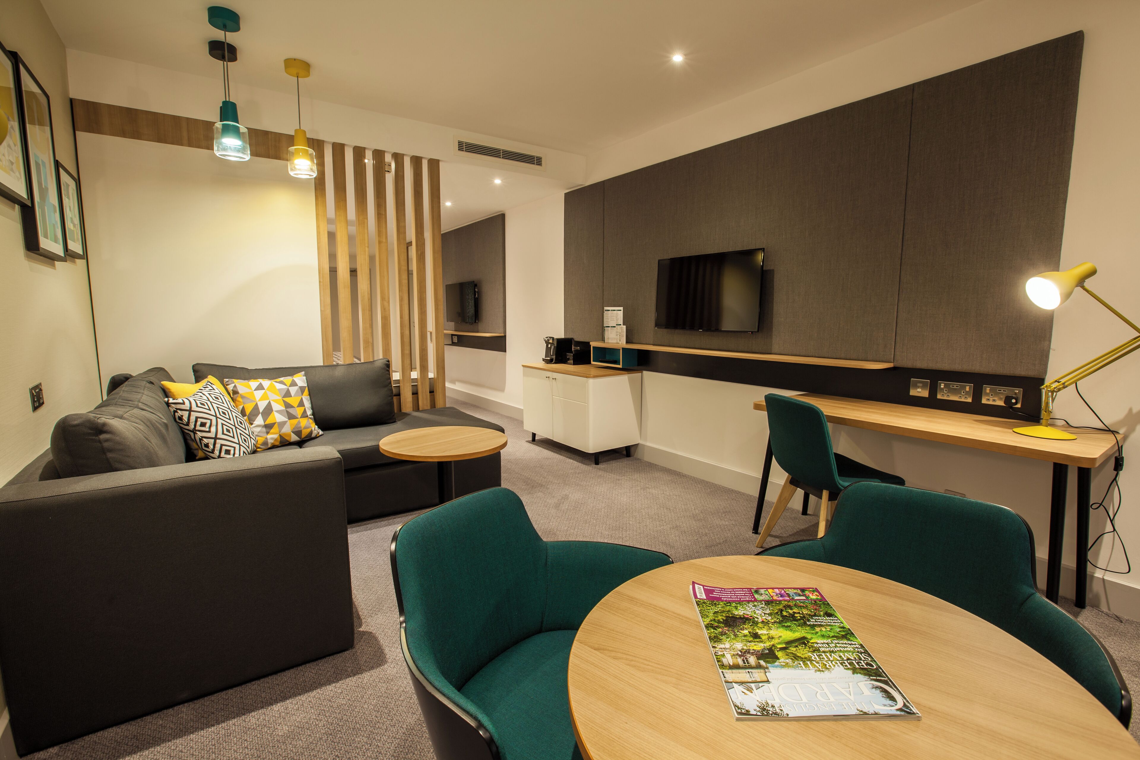 A modern living room with a sofa, chairs, a coffee table, and a TV.