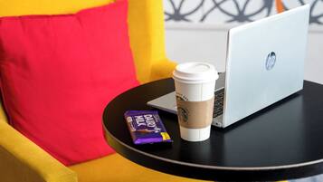 A laptop, a coffee cup, and a chocolate bar on a small table.