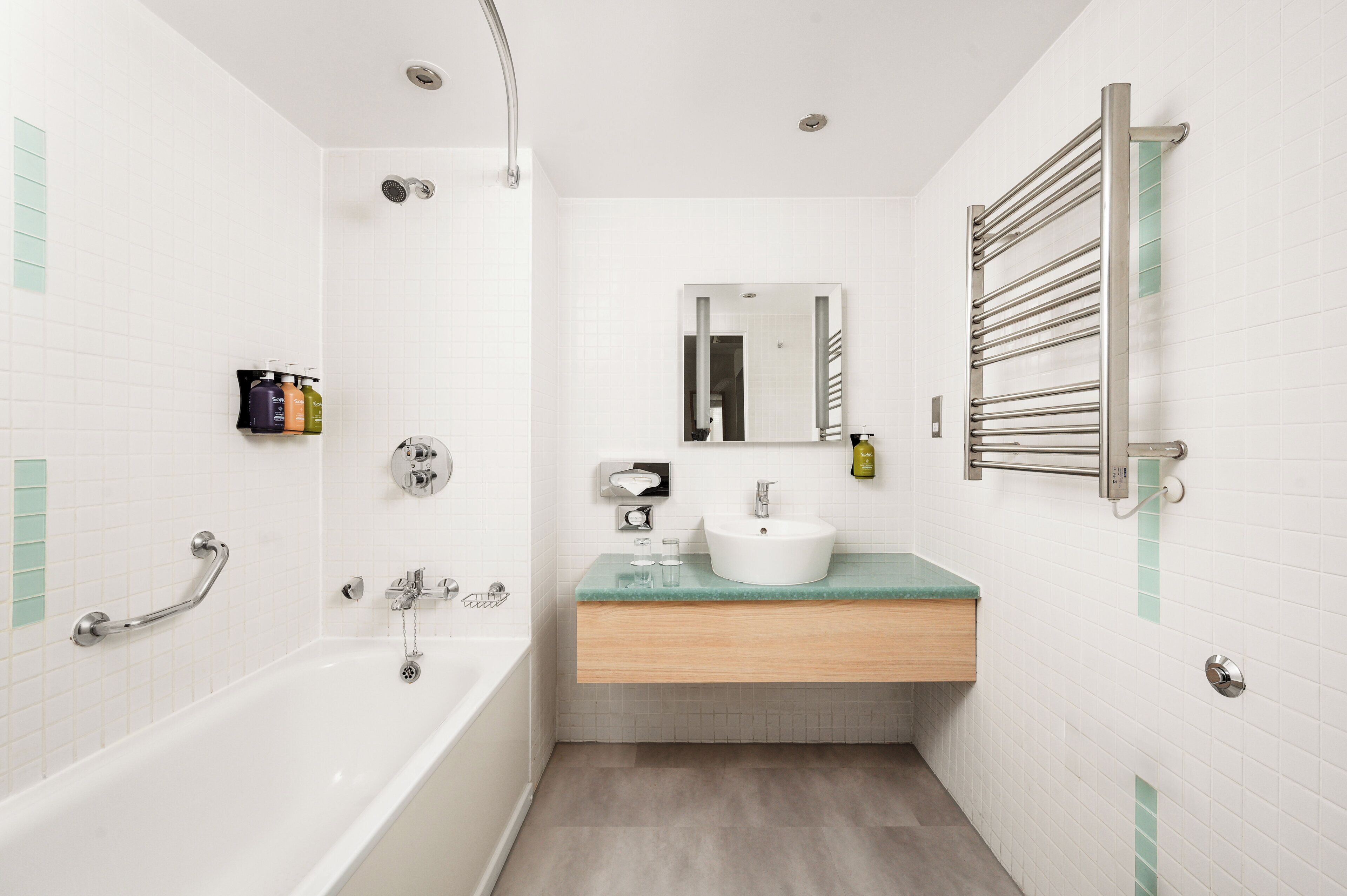 Ein modernes Badezimmer mit einer Badewanne, einem Waschbecken, einem Spiegel und einem Handtuchhalter.
