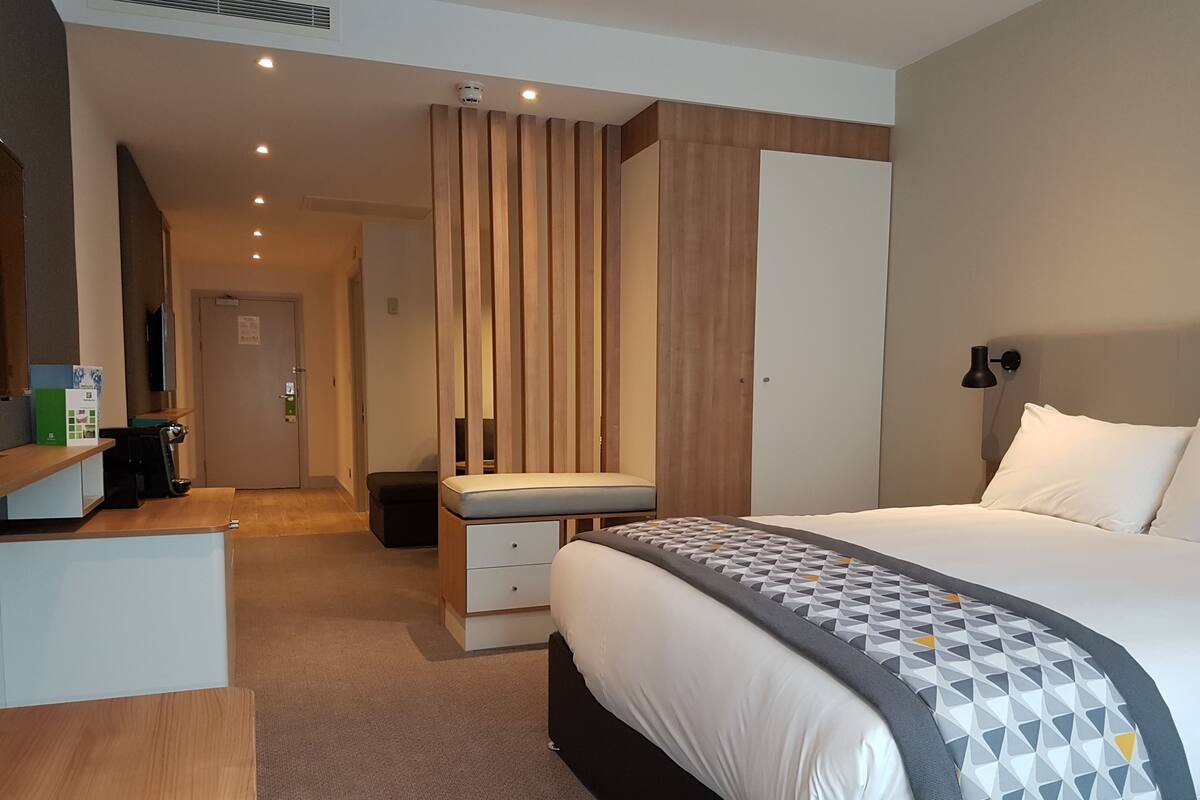 A modern hotel room with a large bed, a desk, and a seating area.