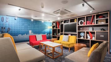 A modern living room with a blue wall mural, a red sofa, yellow armchairs, and a wooden coffee table.