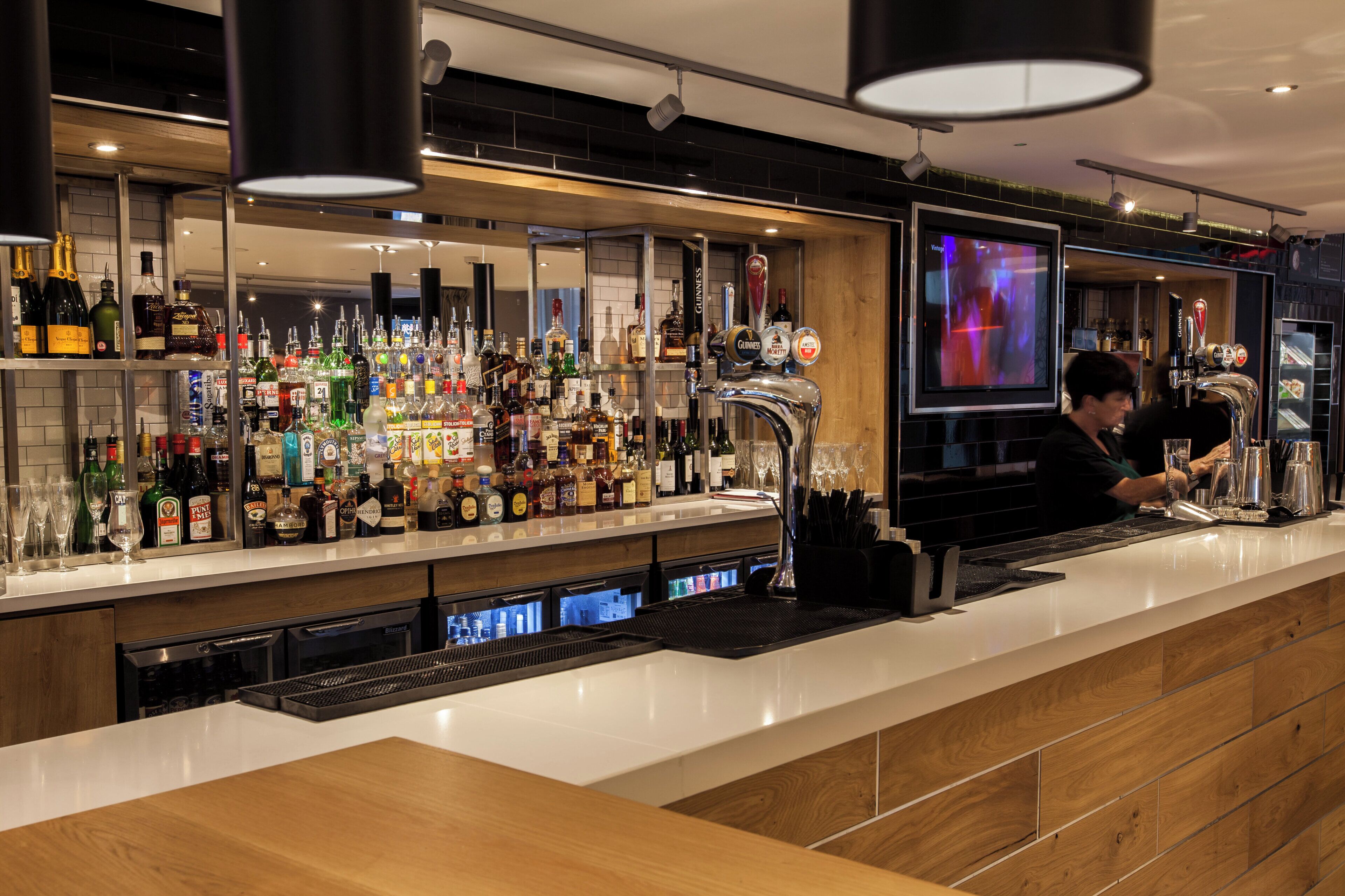A bar area with a variety of liquor bottles, a tap system, and a bartender at work.