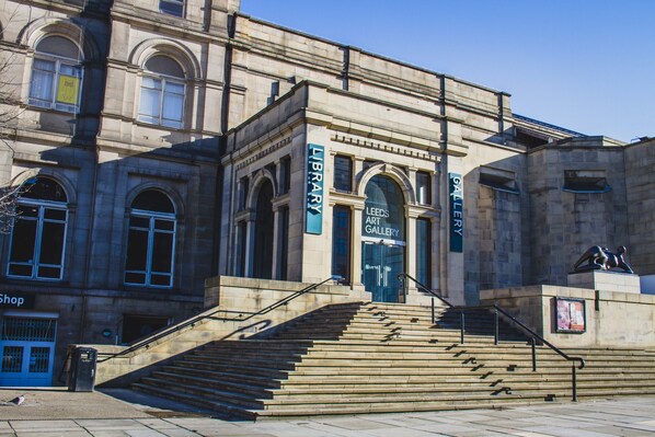 A stone building with a staircase leading to the entrance. There are signs for a library and an art gallery. - 42 The Calls (Leeds)