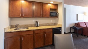 A compact kitchen with wooden cabinets, a built-in microwave, a coffee maker, and a dishwasher. - Holiday Inn Marquette by IHG (Marquette)