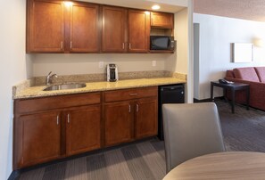 A compact kitchen with wooden cabinets, a built-in microwave, a coffee maker, and a dishwasher. - Holiday Inn Marquette by IHG (Marquette)