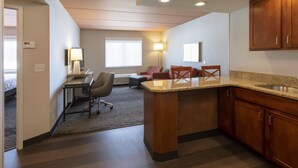 A hotel room with a kitchenette, a desk, a chair, and a sofa. - Holiday Inn Marquette by IHG (Marquette)
