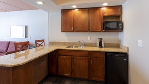 A kitchen with wooden cabinets, a microwave, a sink, and a dishwasher. - Holiday Inn Marquette by IHG (Marquette)