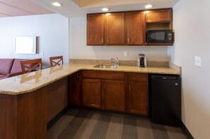 A kitchen with wooden cabinets, a microwave, a sink, and a dishwasher. - Holiday Inn Marquette by IHG (Marquette)