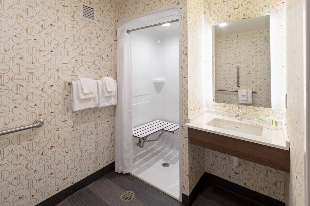 A bathroom with a shower, a sink, and a mirror.