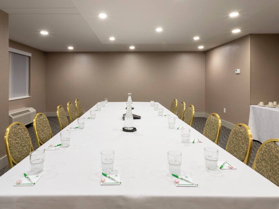 Un salón de conferencias con una mesa larga, sillas y una estación de café.