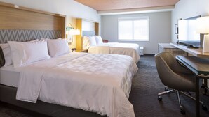 A hotel room with a large bed, a smaller bed, a desk with a chair, a television, and a window. - Holiday Inn Marquette by IHG (Marquette)