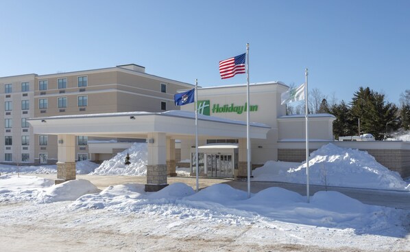 A Holiday Inn hotel with a covered entrance and snow accumulation around the building.