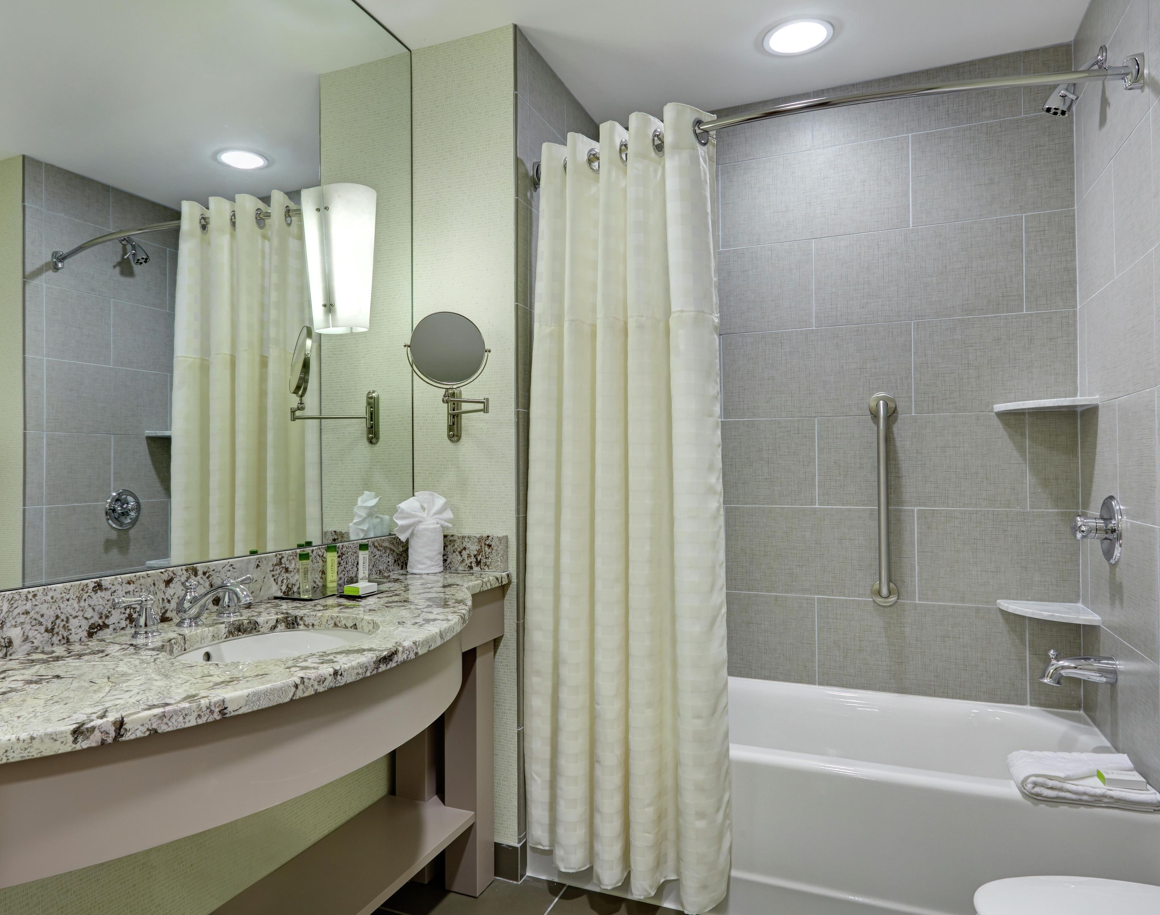 A bathroom with a marble sink, a mirror, a shower with a glass door, and a bathtub.