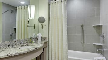 A bathroom with a marble sink, a mirror, a shower with a glass door, and a bathtub.