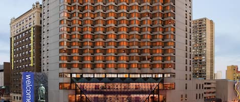 Un hotel moderno de altura con una fachada geométrica distintiva y una entrada destacada.