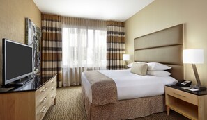 A hotel room with a bed, a TV, a desk with a lamp, and a window with curtains. - DoubleTree by Hilton Philadelphia Center City (Philadelphia)