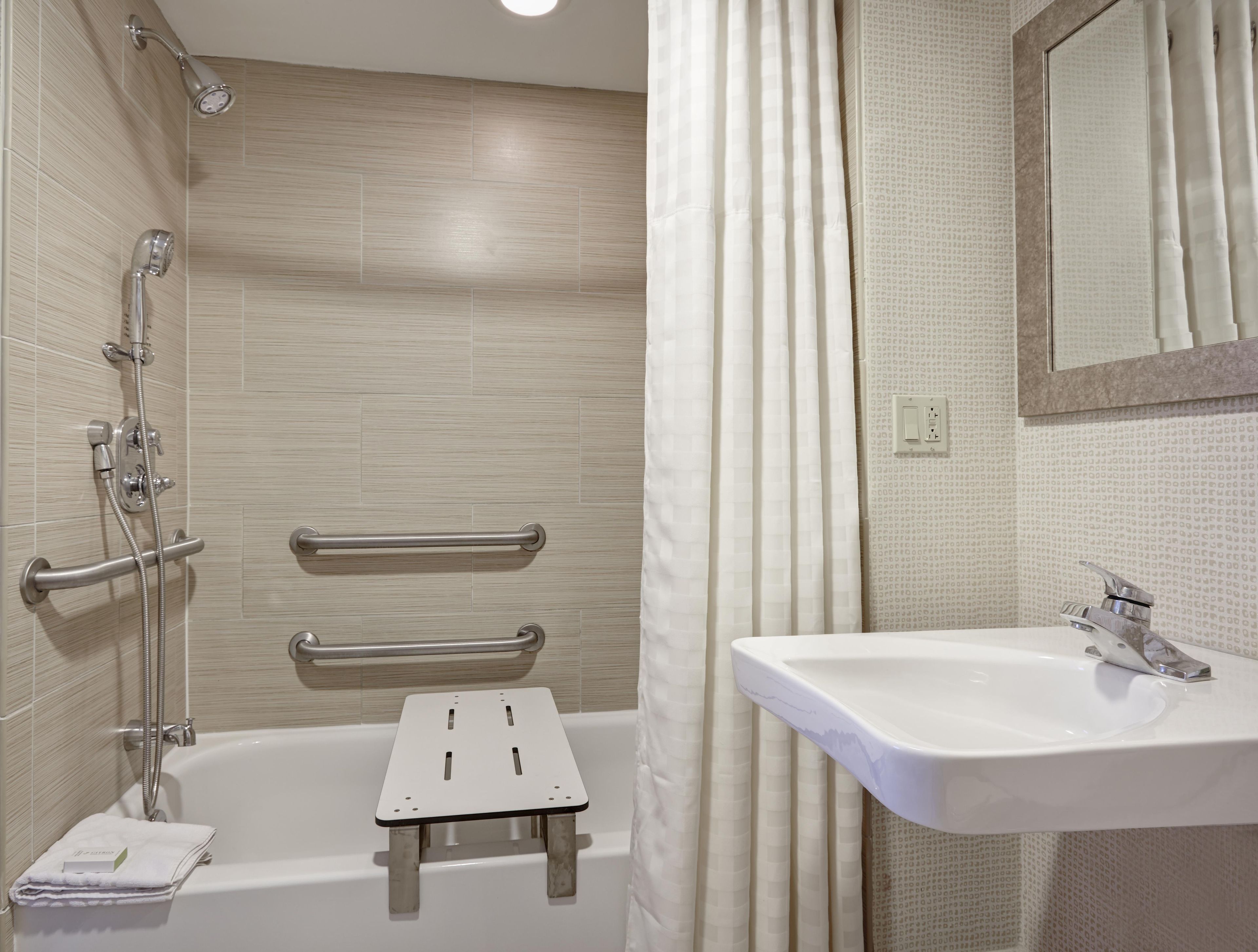 A bathroom with a bathtub, a shower, a vanity with a sink, and a mirror.