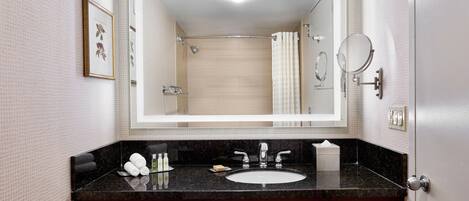 Un baño con un espejo grande, un lavamanos y una ducha.