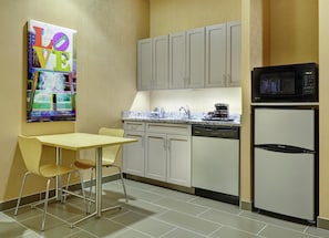 A compact kitchen with a dining area, including a microwave, dishwasher, and a painting on the wall. - DoubleTree by Hilton Philadelphia Center City (Philadelphia)