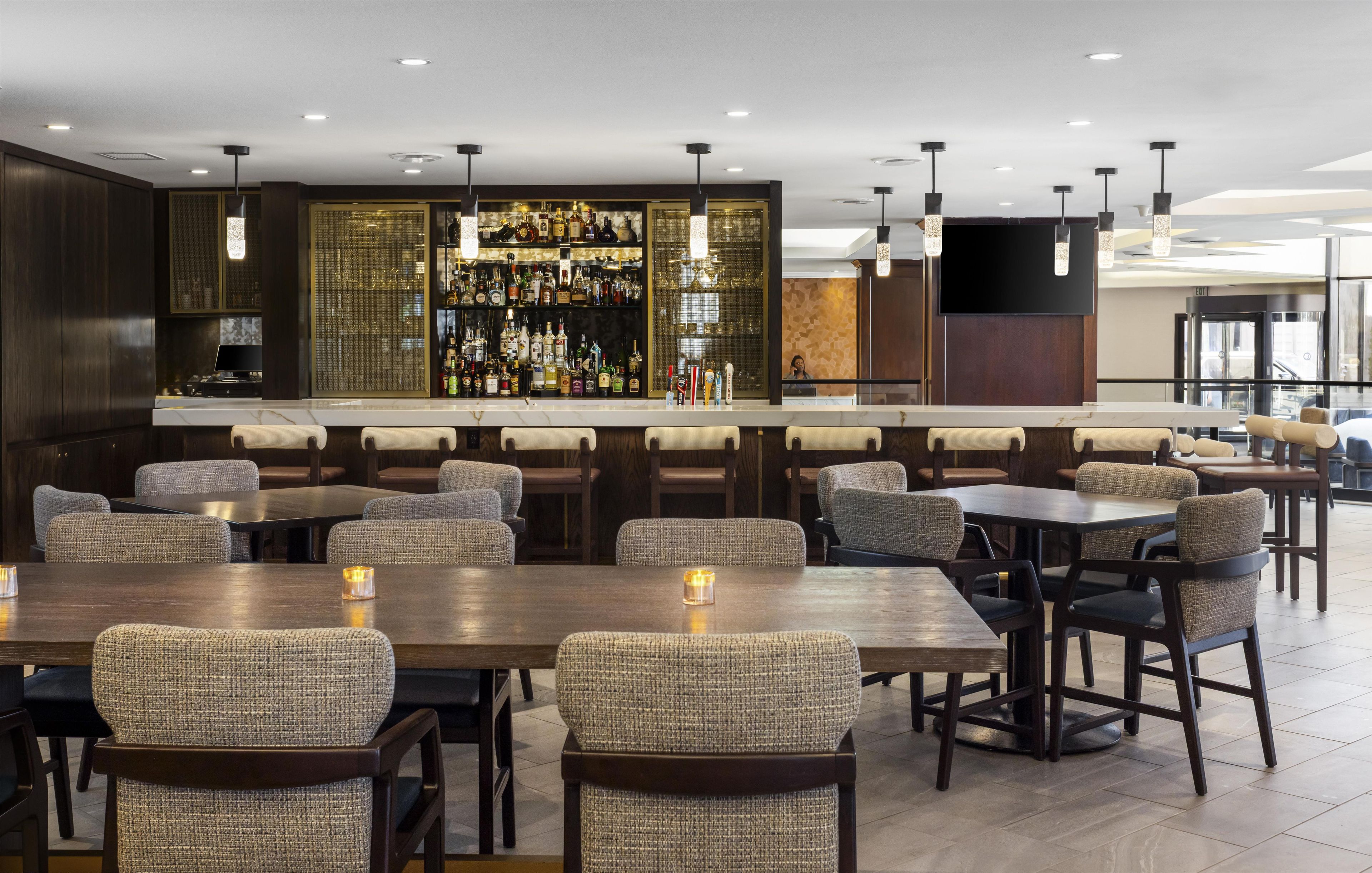 A bar area with multiple seating options, a well-stocked bar, and a modern interior design.