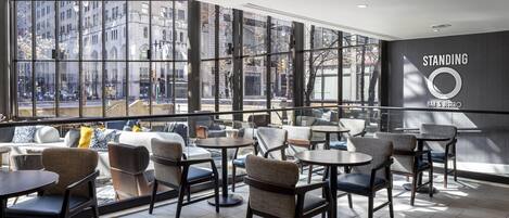 A modern bar and bistro with large windows, comfortable seating, and a prominent logo on the wall.