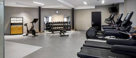 A gym with treadmills, stationary bikes, and dumbbells.