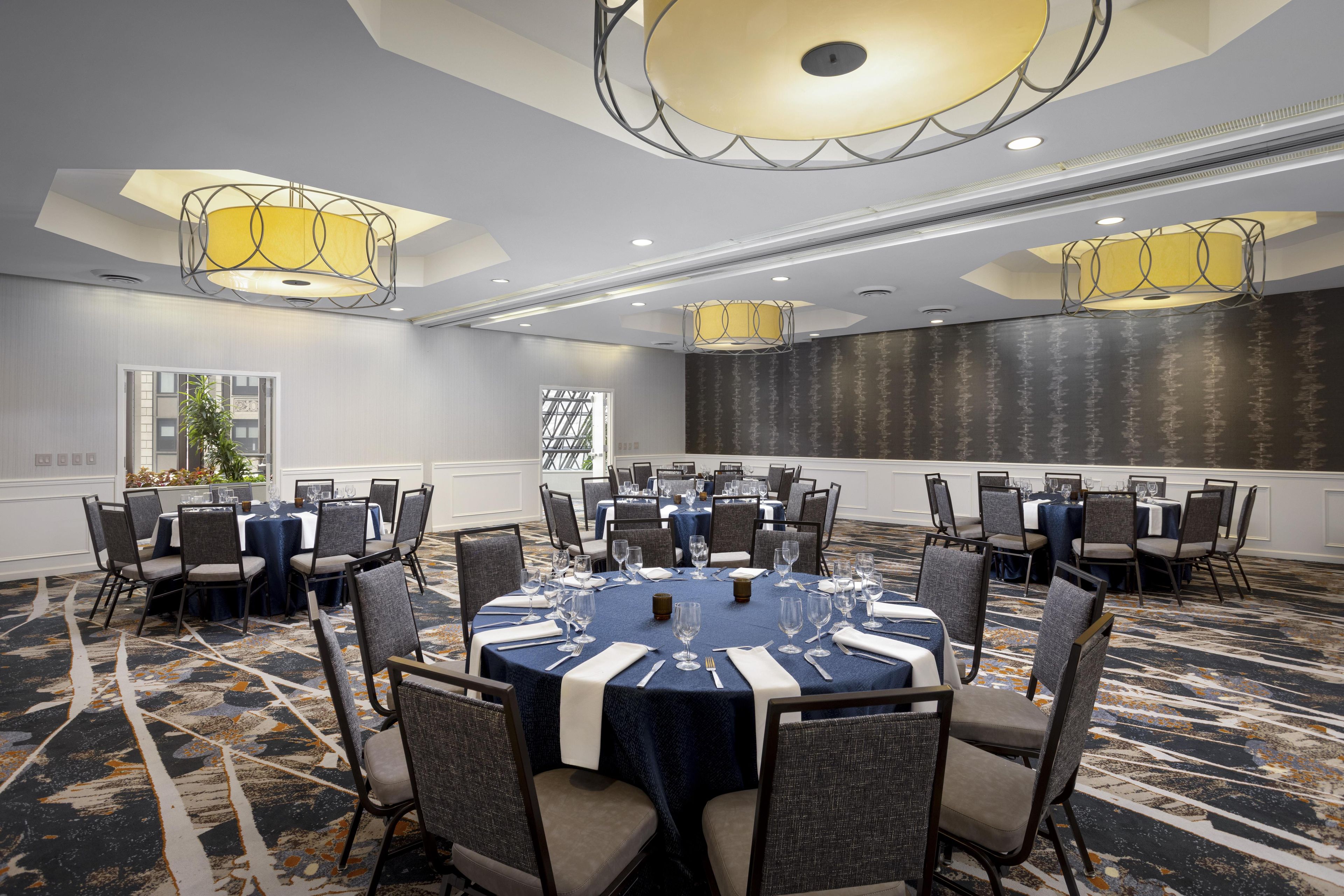 A conference room with round tables, chairs, and chandeliers.