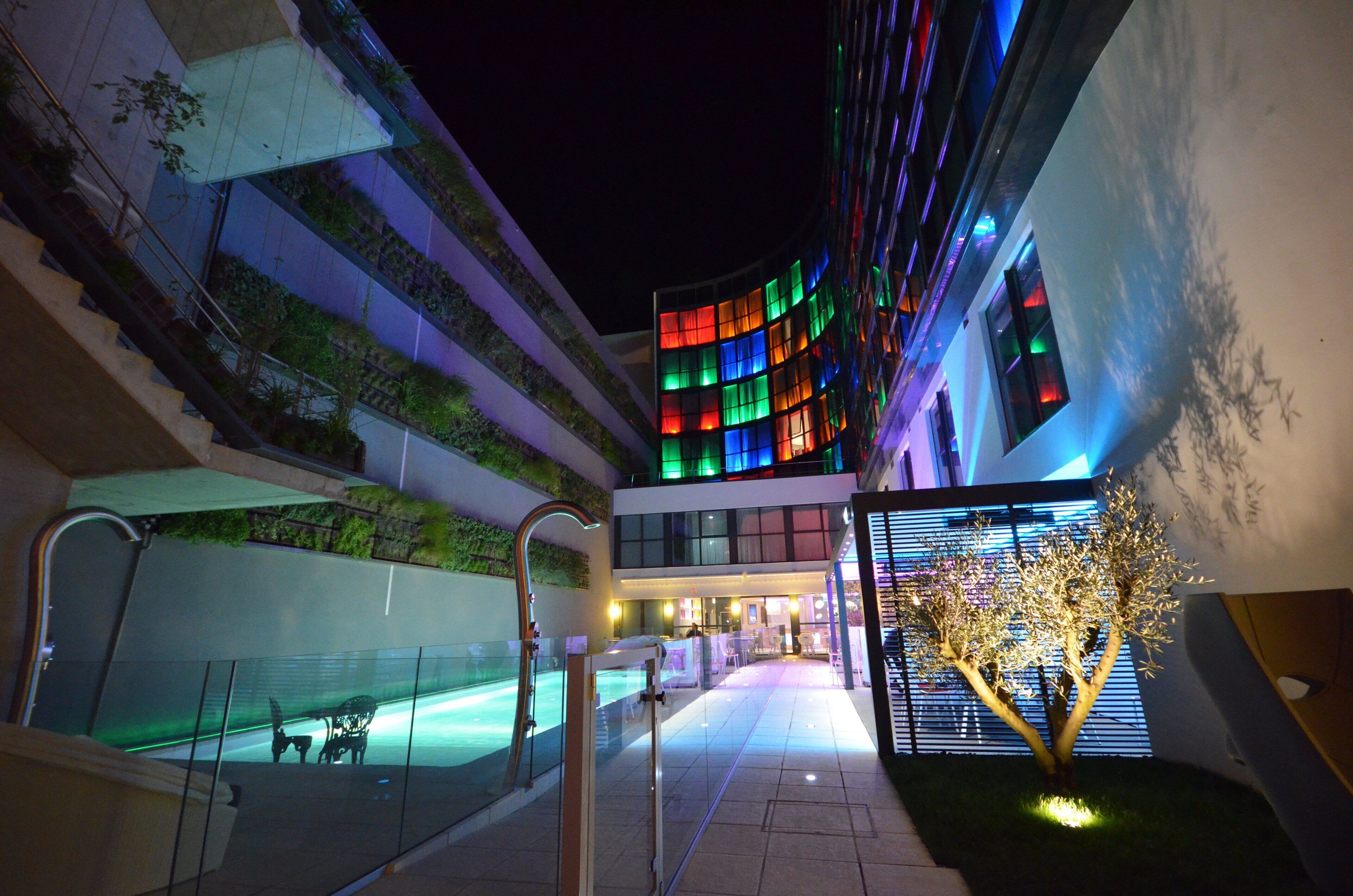 Un hotel moderno con fachada curva, piscina exterior y una escalera que lleva a un nivel superior.