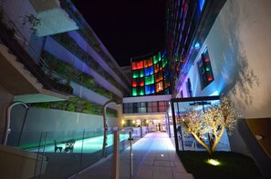 A modern hotel with a curved facade, outdoor pool, and a staircase leading to an upper level.