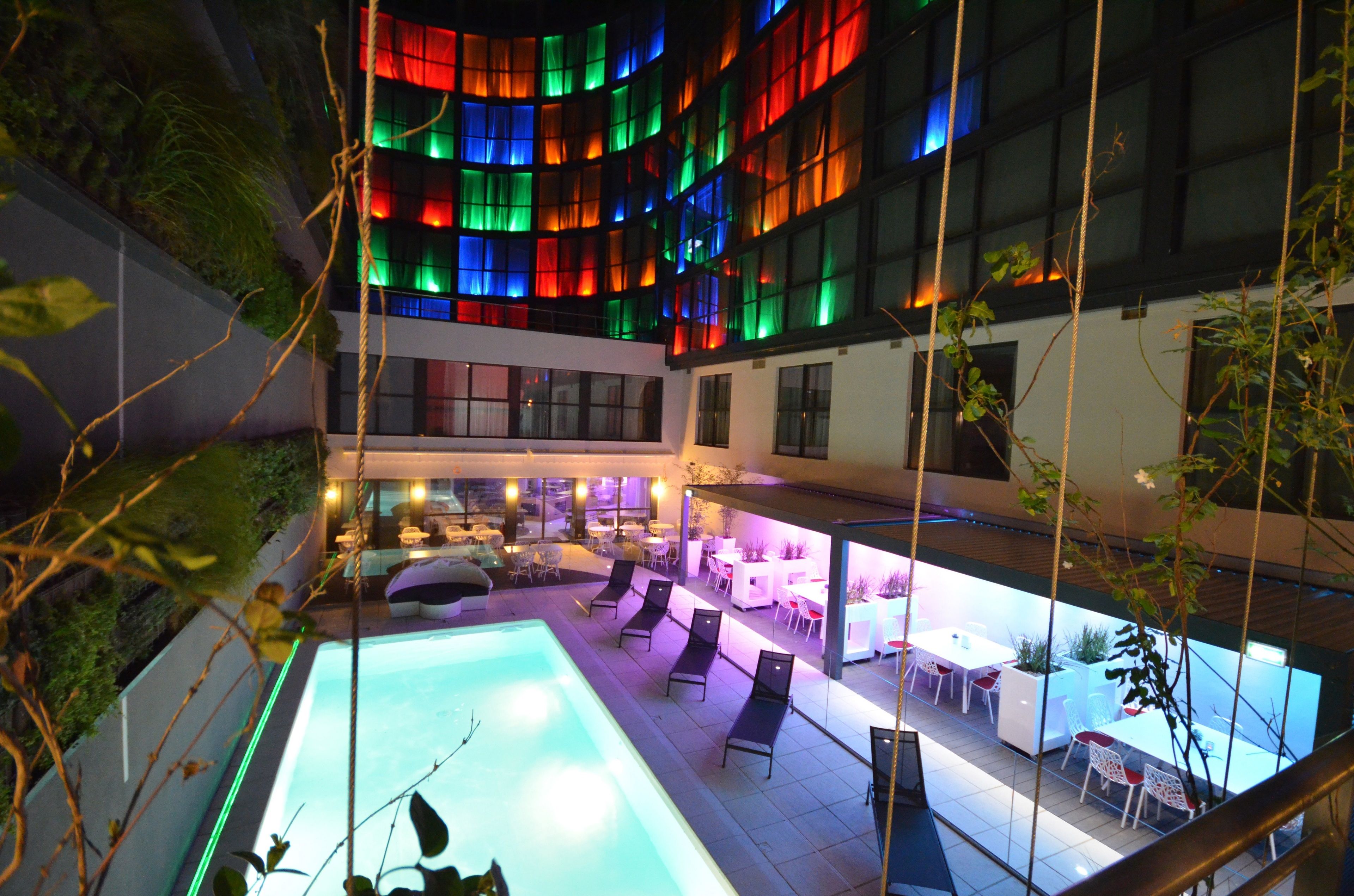 A rooftop pool area with lounge chairs and a bar area.