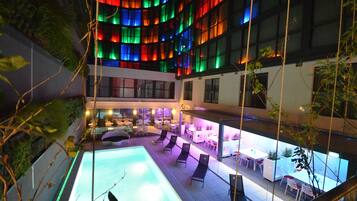A rooftop pool area with lounge chairs and a bar area.